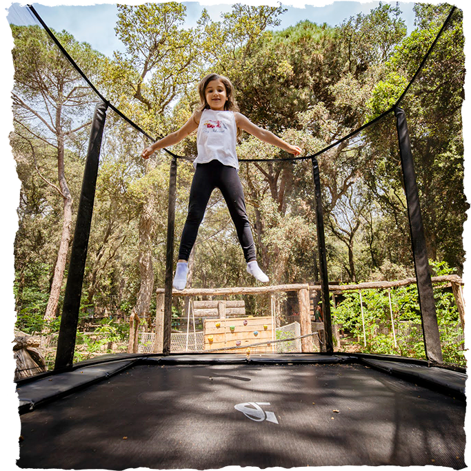 Nena saltant al trampolí acrobàtic al parc d'equilibri Dumbo